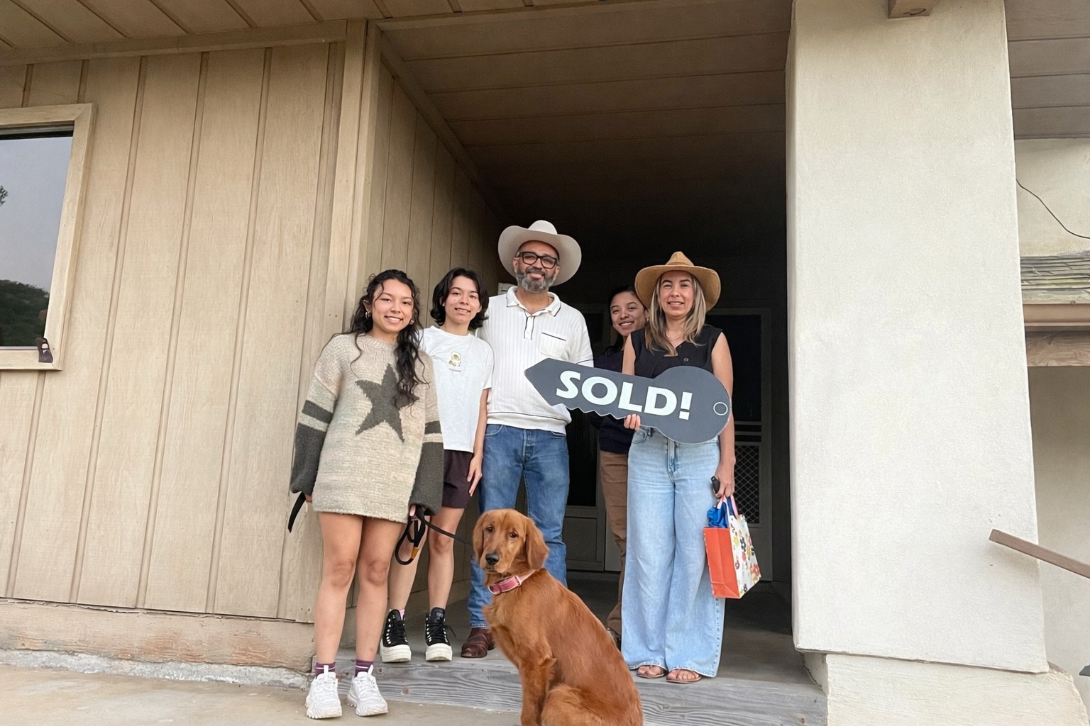 Family celebrating with a SOLD sign at their new San Diego home
