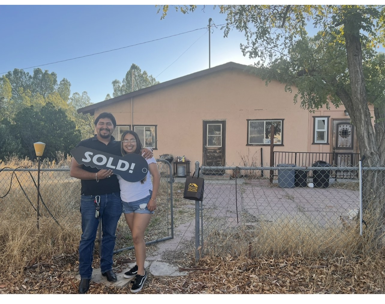 Couple holding a SOLD key in front of their first home
